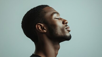 Obraz premium Side profile of a peaceful young man with eyes closed, expressing calm and inner contentment against a neutral background