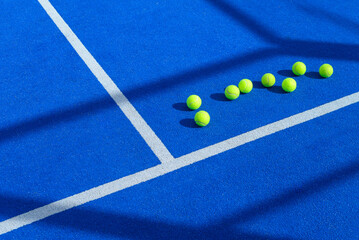 seven balls in a blue padel tennis court, racquet sports background concept