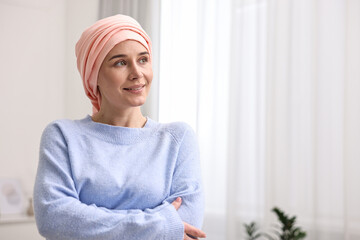 Portrait of smiling woman with cancer in headscarf indoors. Space for text