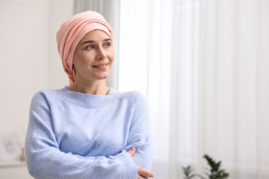 Portrait of smiling woman with cancer in headscarf indoors. Space for text
