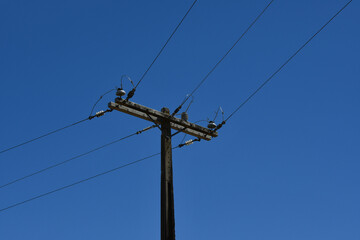 An electric pole of the power distribution network on a blue sky background	