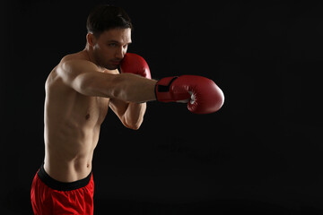 Man in boxing gloves fighting on black background