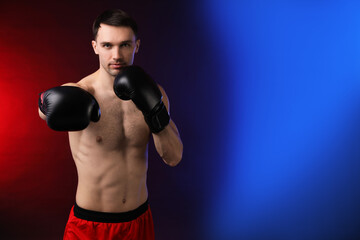 Man with boxing gloves fighting on dark background in neon lights, space for text