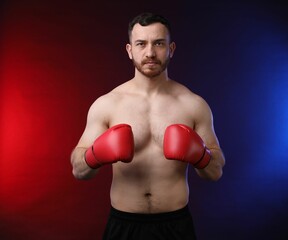 Man with boxing gloves on dark background in neon lights