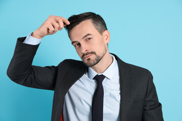 Handsome man stylish his hair with comb on light blue background