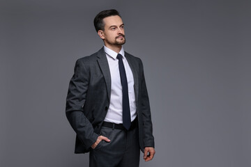 Confident man in classic suit on grey background. Space for text