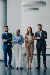 Four confident business people standing with arms crossed in modern office
