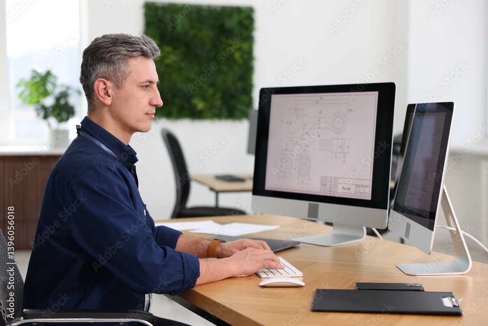 Poster engineer working with digital drawings at table in office