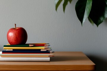Back to school supplies on wooden table. Red apple atop colorful pencils and notebooks