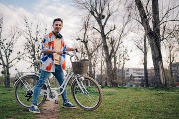 Stylish man posing with bicycle in urban park
