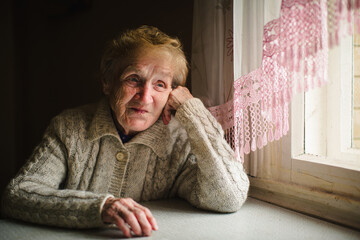 A portrait of an elderly woman sitting at a table, her expression calm and reflective, capturing a moment of quiet dignity.