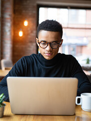 Focused young man working on laptop in café.