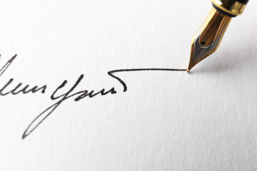 Fountain pen leaving signature on paper, closeup