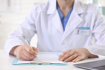 Professional doctor working at white desk in hospital, closeup