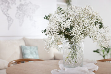 Fototapeta premium Bouquet of beautiful gypsophila flowers and eucalyptus branches in vase on table indoors. Space for text