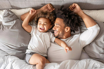 African American father and son lying on bed, smiling under soft natural light