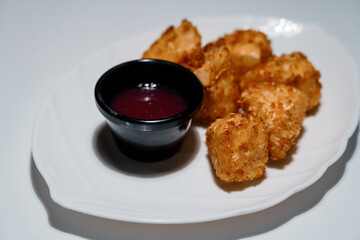 Crispy tater tots served with a vibrant purple dipping sauce on a white plate, studio shot showcasing fast food snack presentation