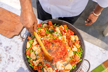 Chef preparing delicious paella outdoors for family gathering
