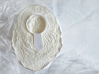 Top view of a plastic measuring scoop placed in fine white powder inside an open bag