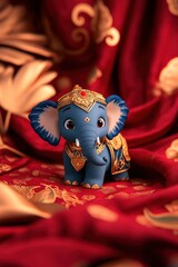 Ornate Indian elephant figurine with elaborate gold detailing on vibrant textile backdrop