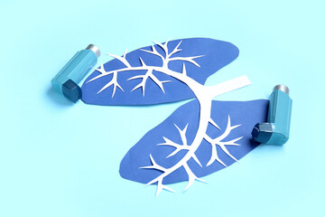 Paper lungs and asthma inhalers on blue background