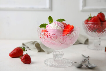 Glass bowl of strawberry ice cream on white table, closeup