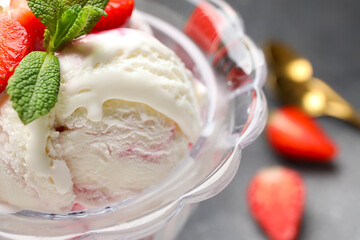 Bowl of vanilla ice cream with strawberries and mint on table, closeup