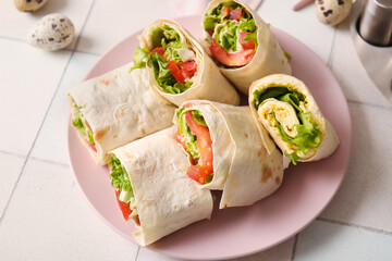 Plate of tasty lavash rolls with tomatoes, egg and greens on white tile background