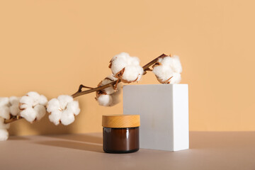 Jar of cosmetic product, plaster podium and cotton branch on color background