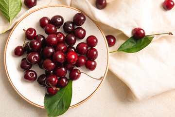 Plate with sweet cherries on white background