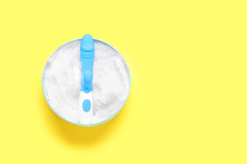 Gift box with feathers and vibrator on yellow background