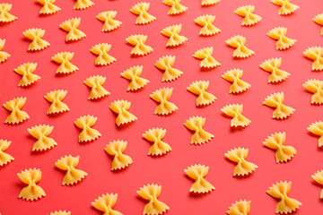 Uncooked farfalle pasta on red background