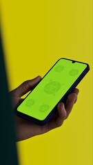 Asian middle aged male using smartphone with a blank green screen. Mobile app video mockup. Vertical phone orientation