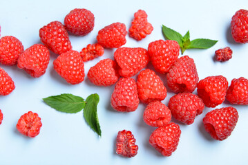 Many fresh raspberries and mint on blue background