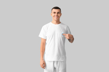 Handsome man with blue ribbon on grey background. Prostate cancer concept