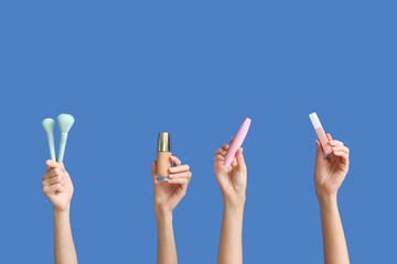 Female hands with decorative cosmetics and makeup brushes on color background