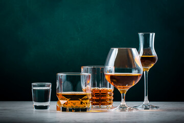 Strong hard alcoholic drinks, spirits, liqueurs, distillates, whiskey and others. Drink background banner. Alcohol set. Green wall