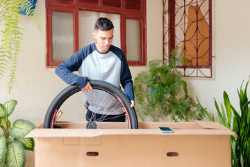 Man unpacking a new mountain bike delivered to his home. He is holding the bike frame and front...