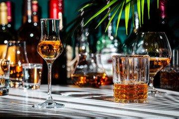 Italian grape vodka grappa in glass and bottles of strong drinks on dark green background