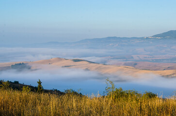 Panorama visto dal crinale che scende da R adicofani lungo la Via Francigena con la bruma mattutina che taglia in due le colline