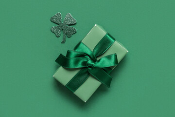 Gift box with clover for St. Patrick's Day celebration on green background