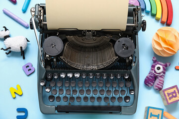 Vintage typewriter and knitted toys on blue background