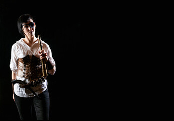 Woman pirate girl holding vintage spyglass with short hair, pistol and eye patch in white shirt on a black background. Dramatic light. Free space