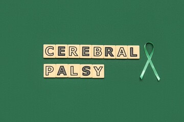 Satin green ribbon and plastic letters with text CEREBRAL PALSY on green background