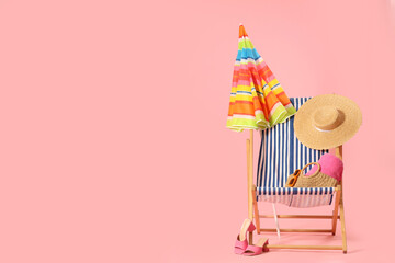 Striped deck chair with colorful umbrella and beach accessories on pink background