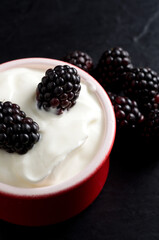 Closeup of Blackberries with Vanilla Yogurt in Red Bowl with Black Background