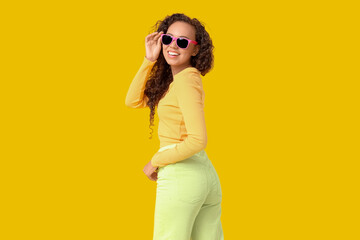 Beautiful African-American woman with sunglasses on yellow background