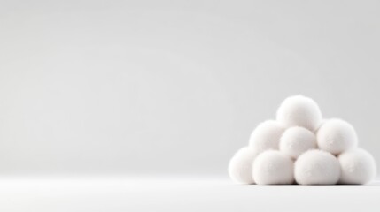 White cotton balls in a pyramid shape on a plain background