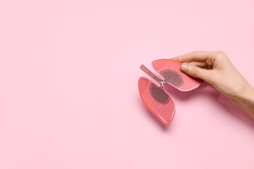 Female hand with paper lungs on pink background