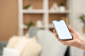 Woman with blank mobile phone at home, closeup